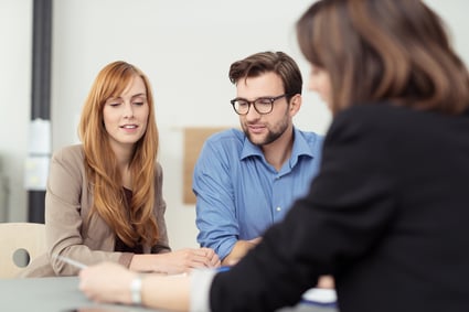 Massachusetts insurance agent making a presentation to a young couple showing them a document which they are viewing with serious expressions