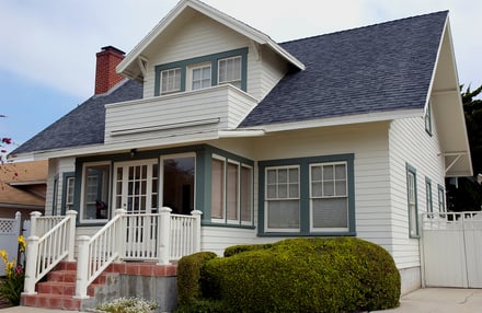 A small white house with and red brick steps for first-time homebuyers