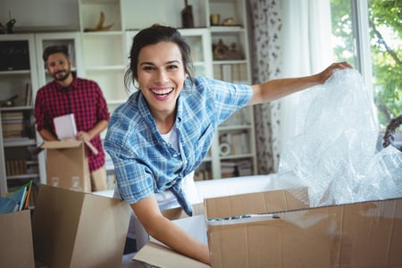 Happy couple unpacking boxes in their new house