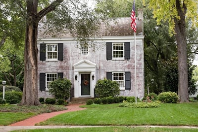 brick colonial home with a flag pole