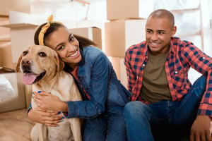 A couple with their dog and packing boxes in new home