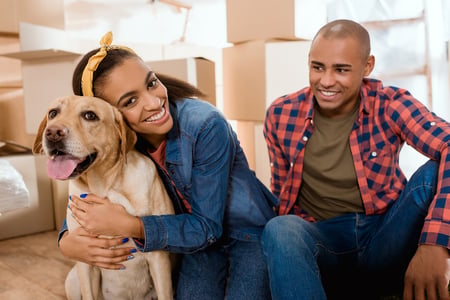 Massachusetts homebuyers moving into their home with their dog, surrounded by moving boxes 