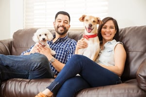 Happy homebuyers on a couch with their puppies