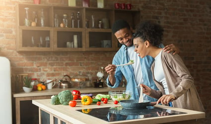 First-time homebuyers in their kitchen making a salad.