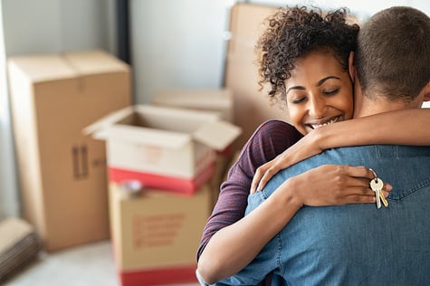 First-time home buyers hugging at their new home. 
