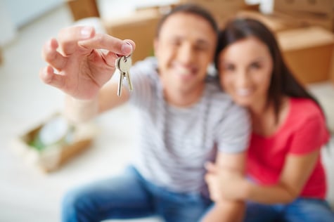 Young, happy couple showing off the keys to their new home.