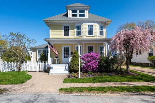 Nicely landscaped New England home with American flag.