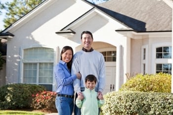 Woman, man and child in front of a white single-family house.