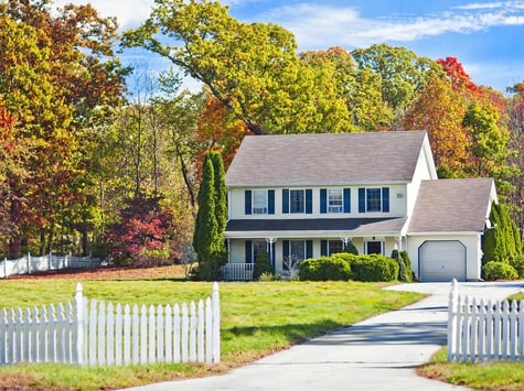 A white Colonial Home with Fall Foliage in the Background